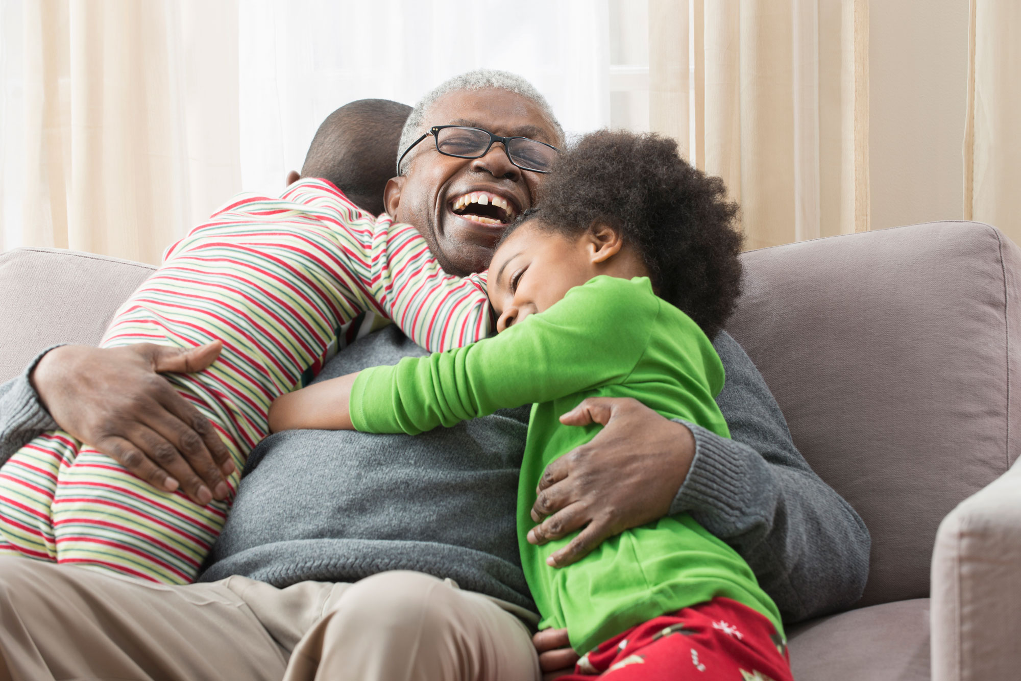 Smiling man hugging grandchildren